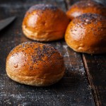 Brioche Buns with Poppy Seeds, Frozen - The Artisan Bakery. Four buns on white background