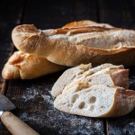 Baguette Demi, Frozen - The Artisan Bakery loose baguette on white background